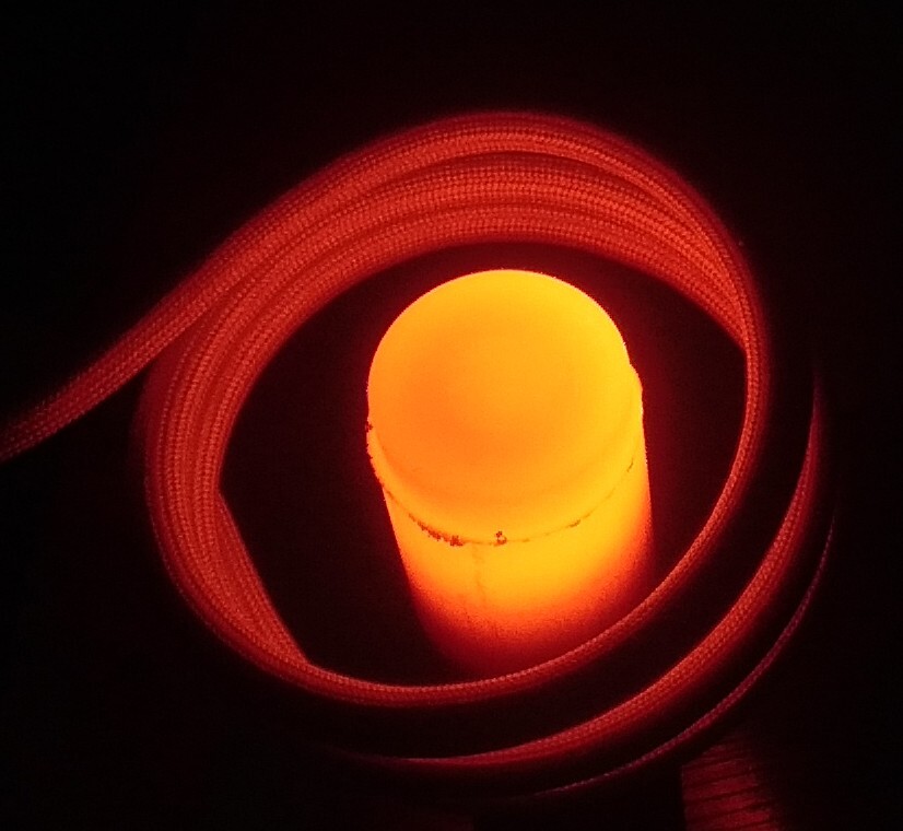 Glowing cylindrical heating element surrounded by an induction coil